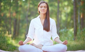 Portrait of calm woman sitting in pose of lotus in natural environment